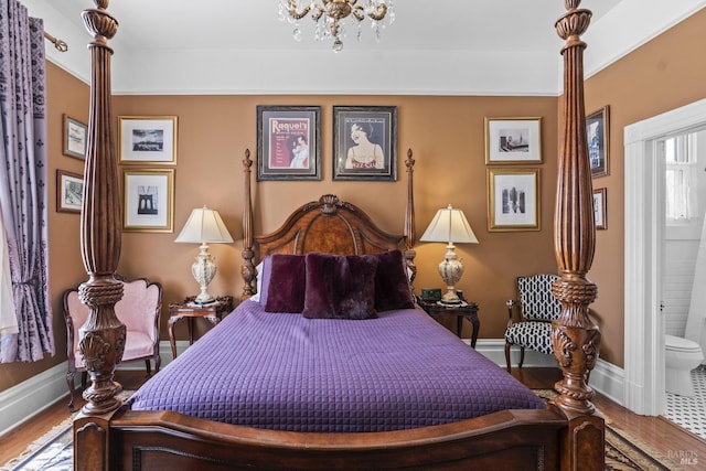 bedroom featuring wood finished floors, a notable chandelier, baseboards, and ensuite bath