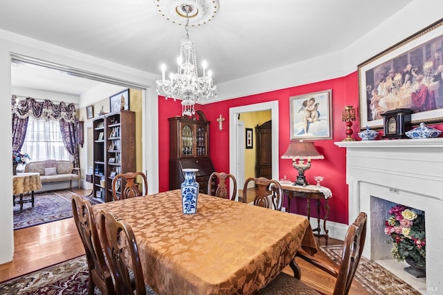 dining space with wood finished floors, a chandelier, and a fireplace with flush hearth