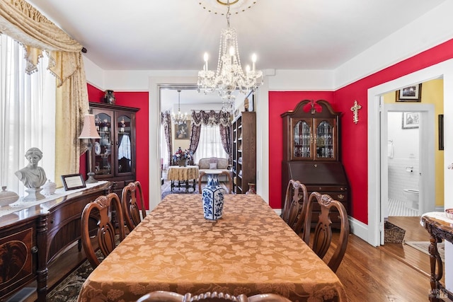 dining area with wood finished floors and an inviting chandelier