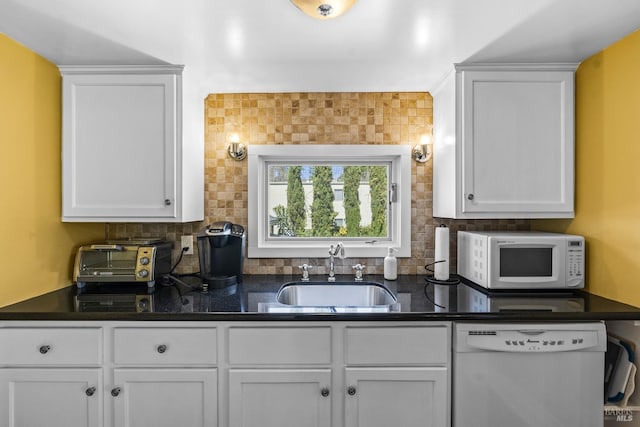 kitchen featuring a sink, white cabinets, dark countertops, and white appliances