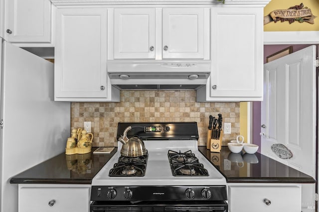 kitchen featuring white cabinets, dark countertops, under cabinet range hood, decorative backsplash, and gas range oven