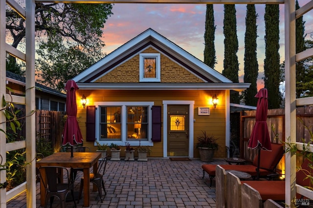 back of house at dusk with a patio area and fence