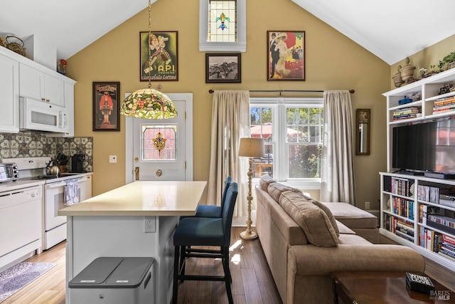 interior space with white cabinets, light wood-type flooring, white appliances, a kitchen bar, and high vaulted ceiling