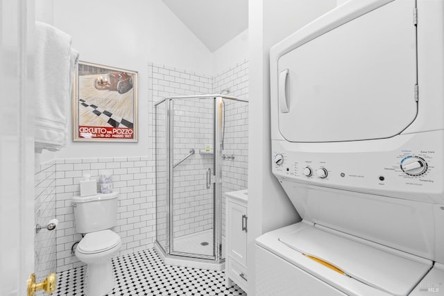 full bathroom featuring tile walls, toilet, a stall shower, and stacked washer / drying machine
