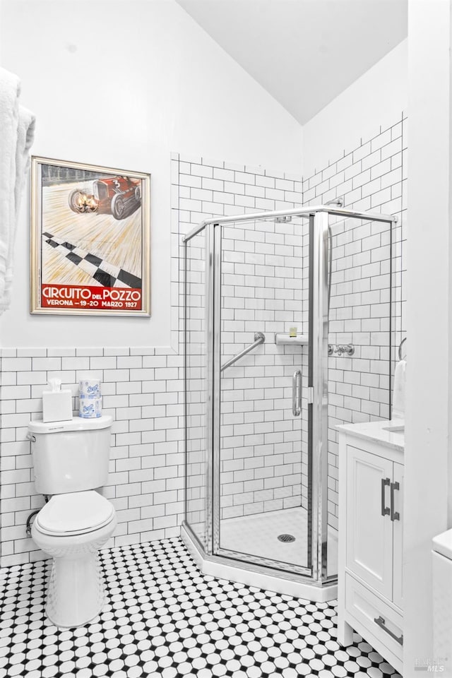 full bathroom featuring a shower stall, vanity, lofted ceiling, and toilet