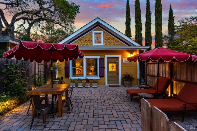 back of property at dusk featuring a patio and fence