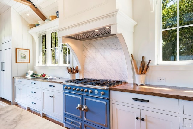 kitchen featuring tasteful backsplash, butcher block counters, blue cabinetry, custom exhaust hood, and range with gas cooktop