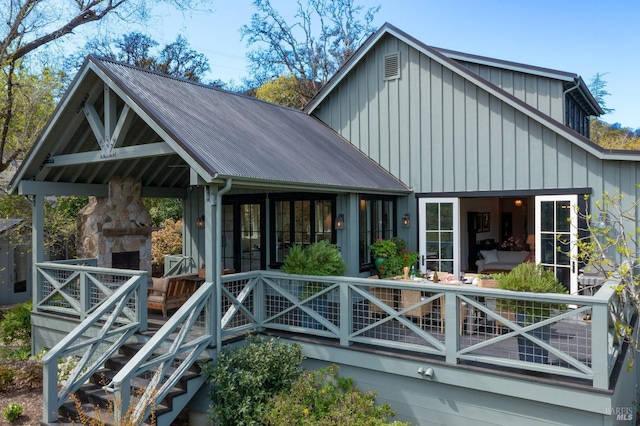 back of property featuring board and batten siding, metal roof, and a stone fireplace