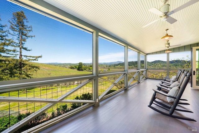 sunroom with a mountain view and a ceiling fan