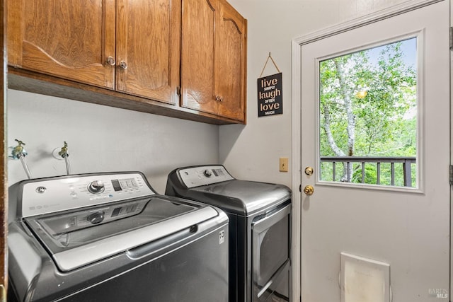 washroom with cabinet space, plenty of natural light, and washer and clothes dryer