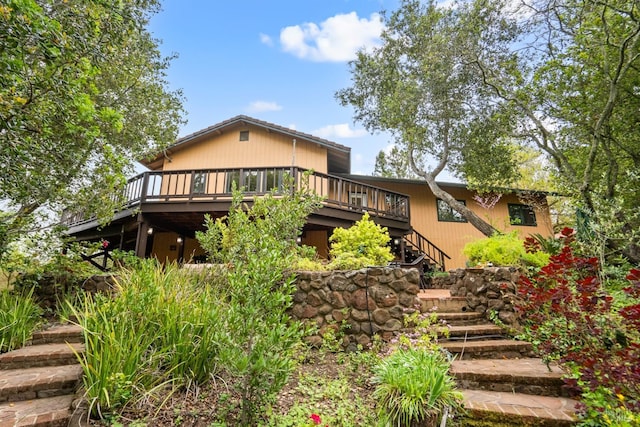rear view of house featuring a wooden deck and stairs