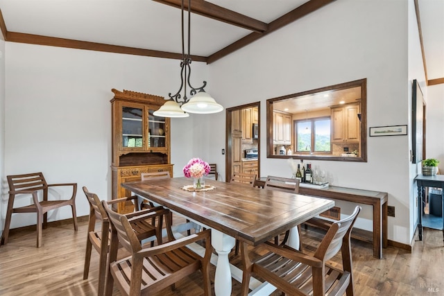 dining area with light wood-style flooring, baseboards, and beamed ceiling