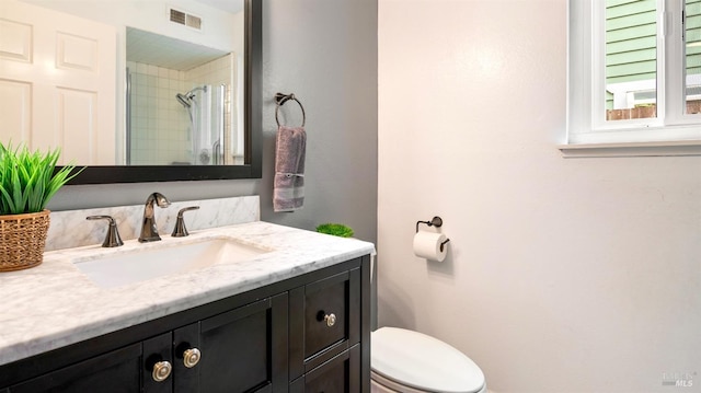 bathroom featuring vanity, walk in shower, visible vents, and toilet