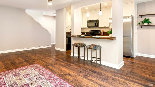 kitchen featuring a breakfast bar, baseboards, dark wood-type flooring, white cabinetry, and black appliances
