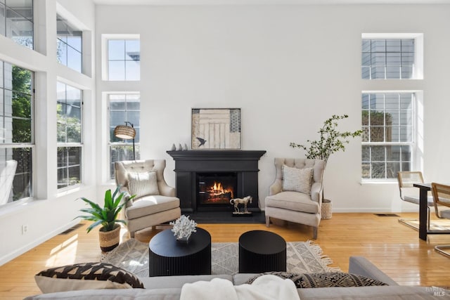 interior space with hardwood / wood-style flooring, baseboards, a glass covered fireplace, and visible vents