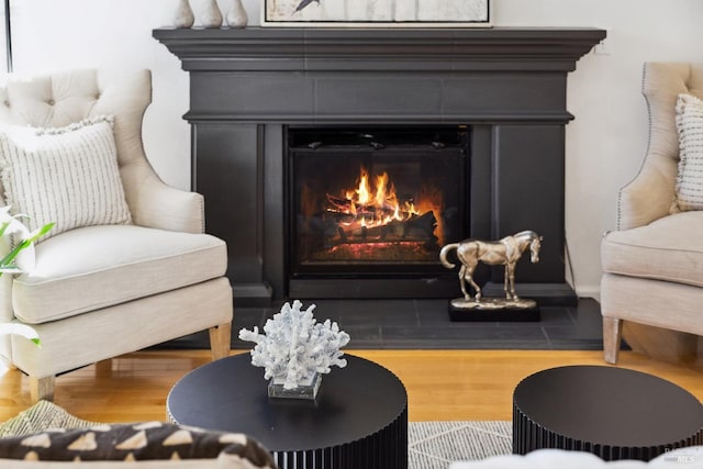 sitting room with a glass covered fireplace and wood finished floors