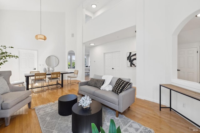 living room with arched walkways, wood finished floors, a high ceiling, and baseboards
