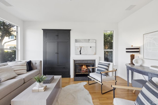living room featuring a tile fireplace, a wealth of natural light, and light wood-style floors