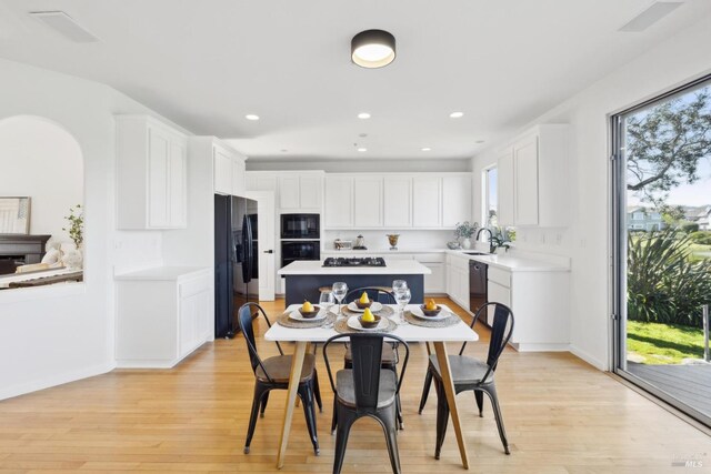 dining area featuring arched walkways, baseboards, light wood-style floors, and recessed lighting