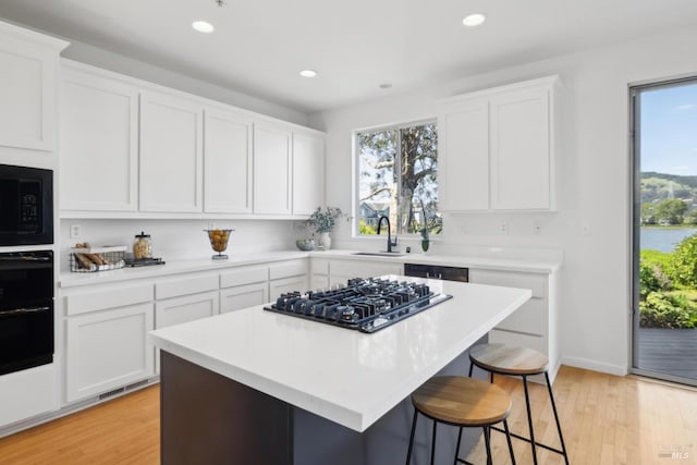 kitchen with black appliances, a sink, a breakfast bar, and plenty of natural light