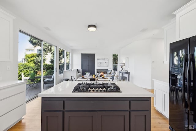 kitchen featuring black refrigerator with ice dispenser, white cabinetry, gas stovetop, and light countertops