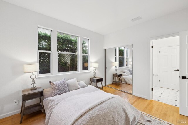 bedroom featuring visible vents, baseboards, and wood finished floors