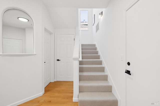 stairs with baseboards, wood finished floors, and visible vents
