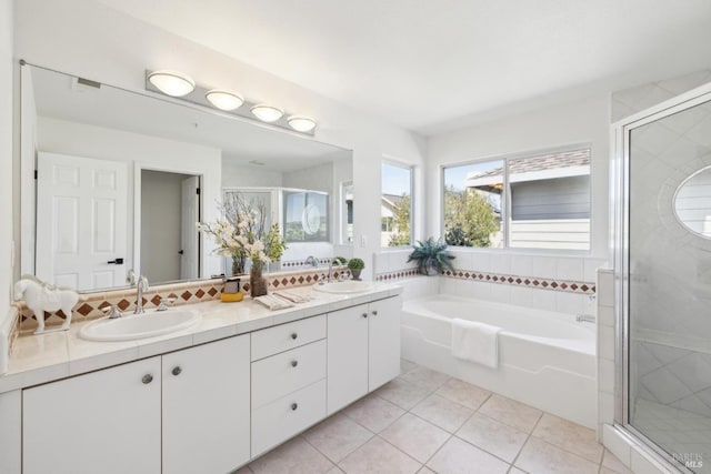 full bath featuring double vanity, tile patterned floors, a stall shower, and a sink