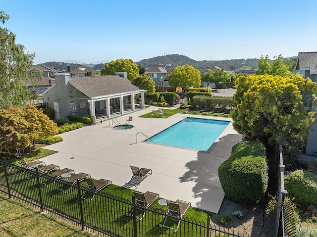 community pool with fence, a patio area, a mountain view, and a residential view