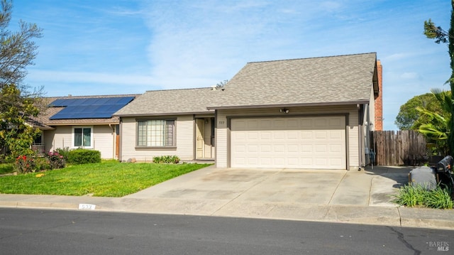 single story home featuring a front yard, roof mounted solar panels, an attached garage, fence, and driveway