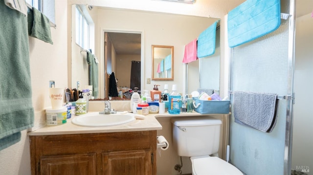 bathroom featuring toilet, an enclosed shower, and vanity