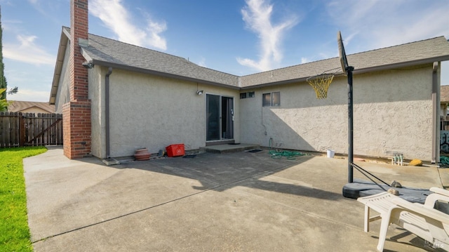 back of house with a chimney, fence, a patio, and stucco siding