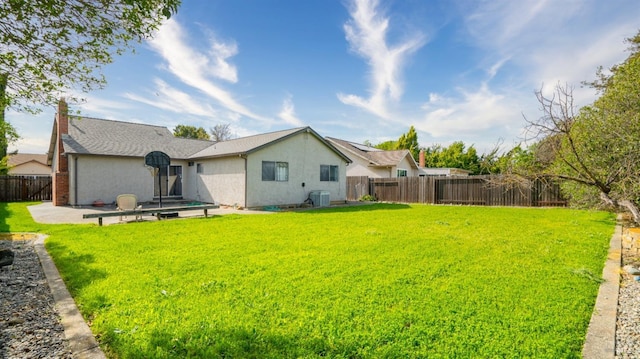 rear view of property featuring a patio area, a fenced backyard, a yard, and stucco siding