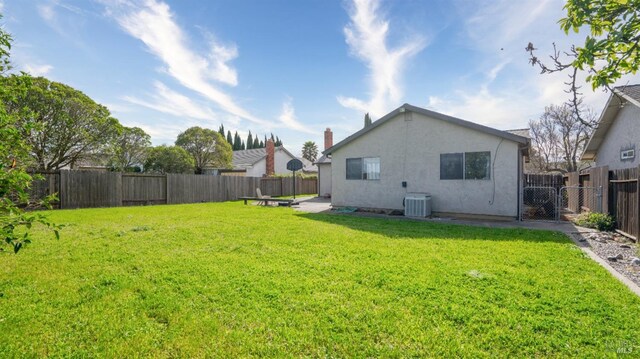 rear view of house featuring central air condition unit, a yard, a fenced backyard, and stucco siding