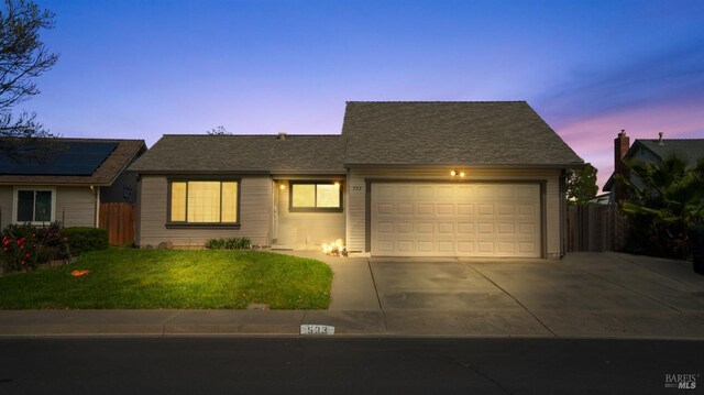 view of front of home with a front yard, fence, an attached garage, a shingled roof, and concrete driveway