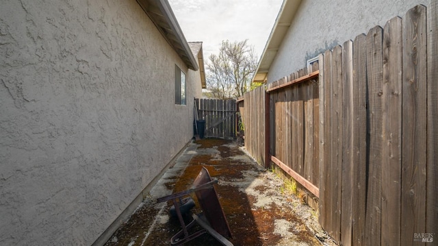 view of side of home featuring stucco siding and fence