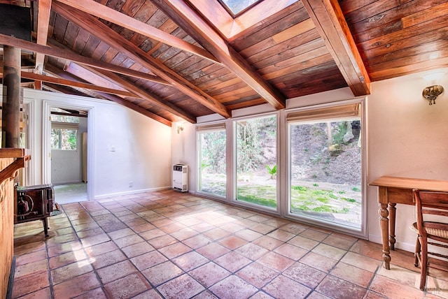 unfurnished living room featuring baseboards, a wood stove, heating unit, wood ceiling, and vaulted ceiling with beams