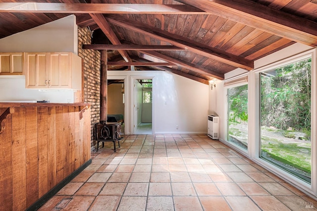 unfurnished living room with a healthy amount of sunlight, a wood stove, and lofted ceiling with beams