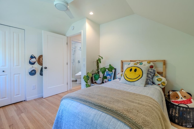 bedroom with a closet, baseboards, ensuite bathroom, wood finished floors, and lofted ceiling