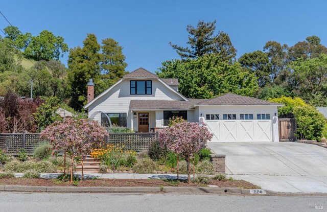 view of front of home featuring an attached garage, concrete driveway, and fence