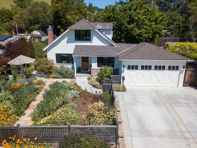 view of front facade featuring driveway, an attached garage, fence, a shingled roof, and covered porch