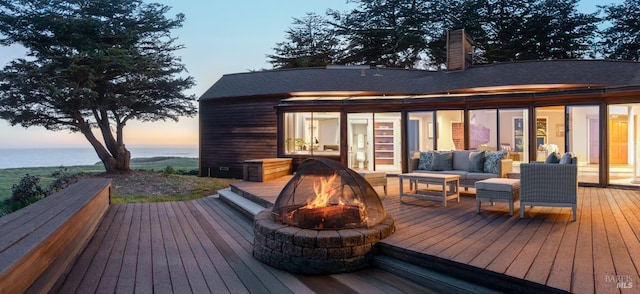 deck with a water view and an outdoor living space with a fire pit