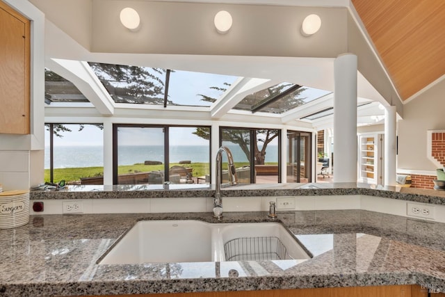 interior space with a water view, dark stone countertops, and a sink