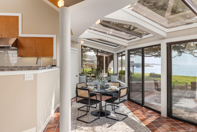 sunroom / solarium featuring a water view and a sink