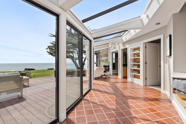 sunroom featuring a water view, tile patterned flooring, and a skylight
