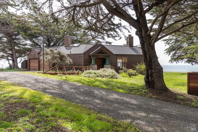 view of front of property with roof with shingles, a chimney, and an outbuilding