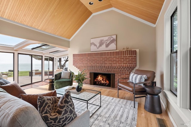 living area featuring visible vents, wooden ceiling, a water view, a fireplace, and lofted ceiling with skylight