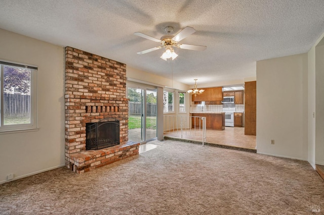 unfurnished living room featuring light colored carpet, a fireplace, a textured ceiling, ceiling fan with notable chandelier, and baseboards