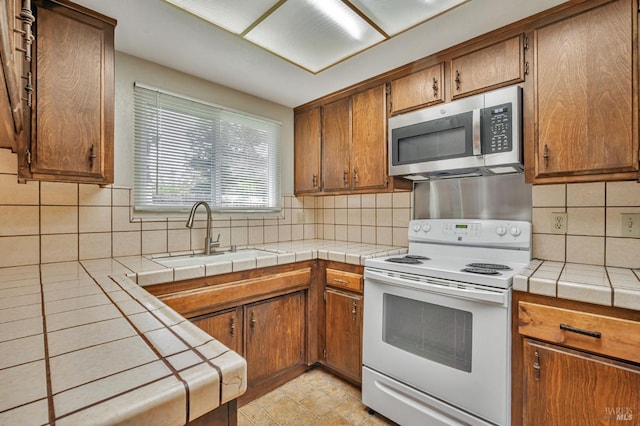 kitchen featuring decorative backsplash, stainless steel microwave, white electric stove, and a sink