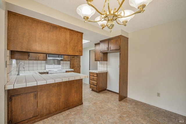 kitchen featuring decorative backsplash, white range with electric cooktop, stainless steel microwave, a chandelier, and a sink